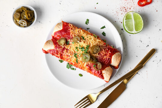 Plate with tasty cooked enchilada on white background