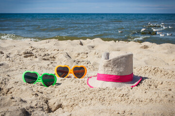 Sunglasses and straw hat on sand at beach. Sun protection while sunbathing. Travel and vacation time