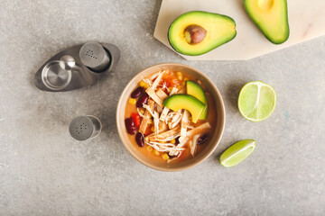 Bowl of tasty chicken enchilada soup on grey background
