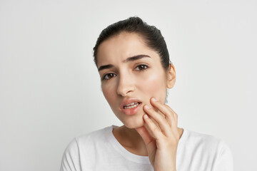 woman in white t-shirt holding face dental problems health dentistry