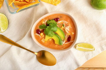 Bowl of tasty chicken enchilada soup on table