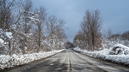 Typical view of US backroad motorway after a snow storm between forests