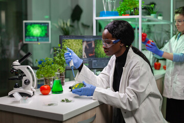 Biologist scientist african woman researcher taking genetic solution from test tube with...