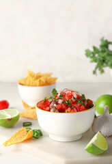 Bowl of tasty Pico de Gallo salsa and nachos on table