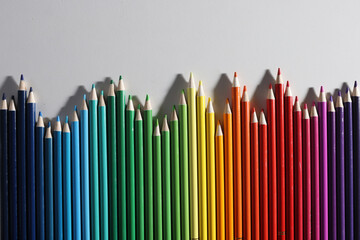 Colored pencils of different shades lie in row on white background