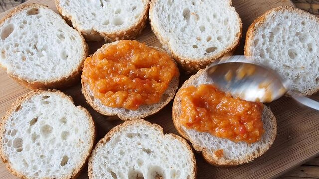 Cooking sandwiches from a slice of French baguettes and zucchini caviar tomatoes onions. Homemade vegetarian food. Canned stewed vegetable wooden background.