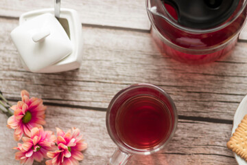 Morning tea is on the table. Flowers and biscuits lie nearby.