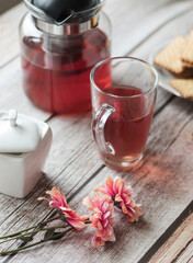 Morning tea is on the table. Flowers and biscuits lie nearby.