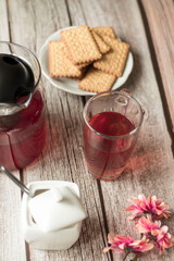 Morning tea is on the table. Flowers and biscuits lie nearby.