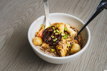 Malaysian noodles laksa soup with chicken, prawn and tofu in a bowl on wooden background