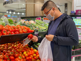 Asian man wearing medical face mask while shopping at grocery store