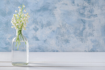 Vase with beautiful lily-of-the-valley flowers on color background