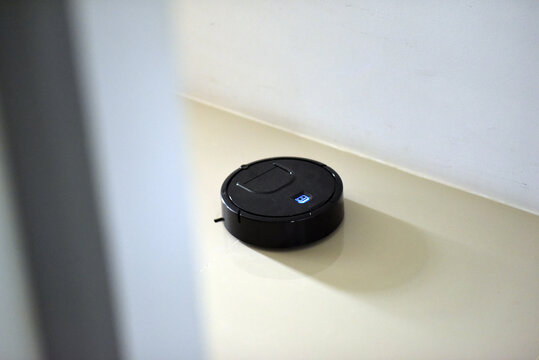 Black robot vacuum cleaner on tiled floor