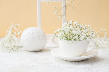 Cup with beautiful gypsophila flowers on table near color wall