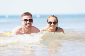 Obraz premium Young happy beautiful couple woman and man lying in sea water