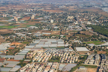 Aerial view of Antalya suburb with houses, greenhouses and fields in Turkey. View from a plane