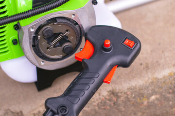 the engine of the new garden trimmer with the unscrewed rod and the control handle of the trimmer close-up