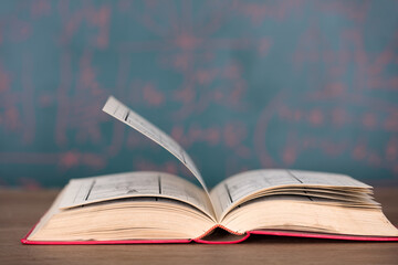 An opened book in front of the blackboard