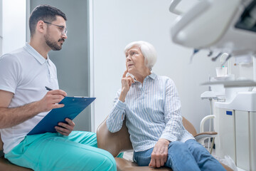 Male young dentist showing the results of xray to his female patient