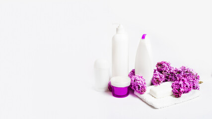 Fototapeta na wymiar organic body care products and space for text on white background with lilac flowers. Cosmetic products, toiletries for hygiene.