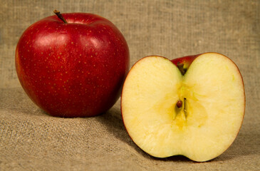 Large red apples on a fabric background. Apples whole and halved. Fruit on a background of burlap. 