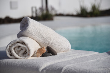 Rolled towels, stones, and a shell on the poolside