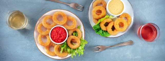 Calamari rings panorama. Deep fried squid rings with green salad, wine and various sauces, top shot, flat lay