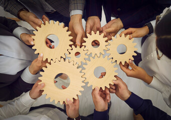 Team of business people connect cogwheels as metaphor for good teamwork, cooperation, partnership...
