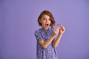 Teen age Girl in blue summer flower print dress holding pop it antistress toy on lavender background, isolate. 