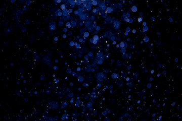 Glittering stars of blue bokeh on black background