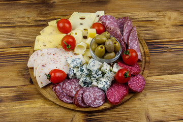 Antipasti platter with olives, cherry tomatoes, assortment of italian salami and cheese on a wooden table