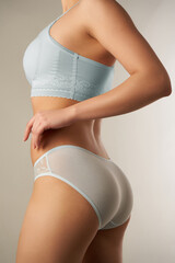 Cropped shot of slim lady in light blue top and pale blue slip panties with mesh and floral design....