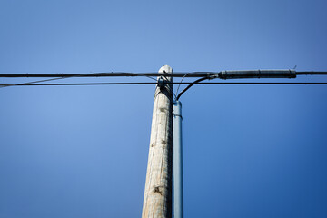 Electric wooden pole under a blue sky.
Bottom view of a utility pole supporting an electrical...