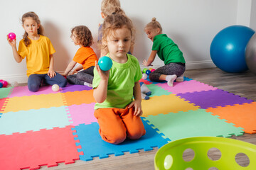 Lovely toddler boy playing with small balls and plastic basket