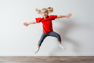Happy jumping preschool girl in red t-shirt