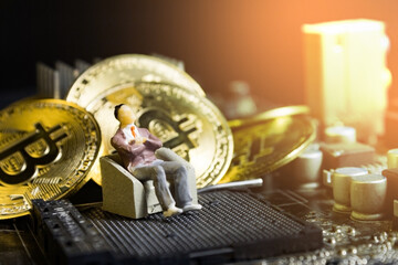 miniature businessman sitting on chair on computer mainboard with pile of bitcoins. concept of crypto currency investment.