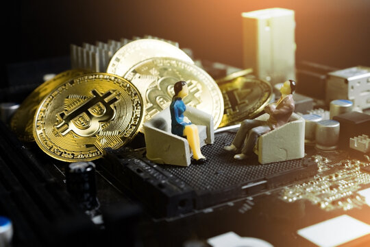 miniature businessman and women sitting on chair on computer mainboard with pile of bitcoins. concept of crypto currency investment.