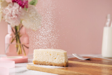 Slice of tasty homemade cheesecake with flowers and miilk on pink background. Healthy organic summer dessert pie.