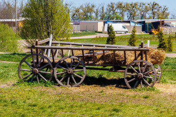 Fototapeta na wymiar Old wooden cart with hay at farmyard
