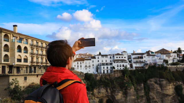 Back view of  Young Tourists man taking pictures by smartphone at the city town in Ronda,spain