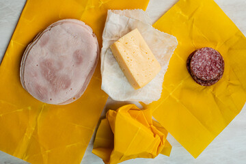 Cheese, salami and ham slices wrapped into beeswax paper - obrazy, fototapety, plakaty