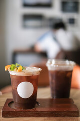 Iced black coffee with orange juice. A plastic cup of espresso coffee shot with orange juice at coffee cafe. (isolated)