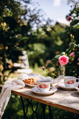 tea party from vintage cups with saucer top view. herbal tea with fresh strawberries. tea party outdoors in the rose garden.