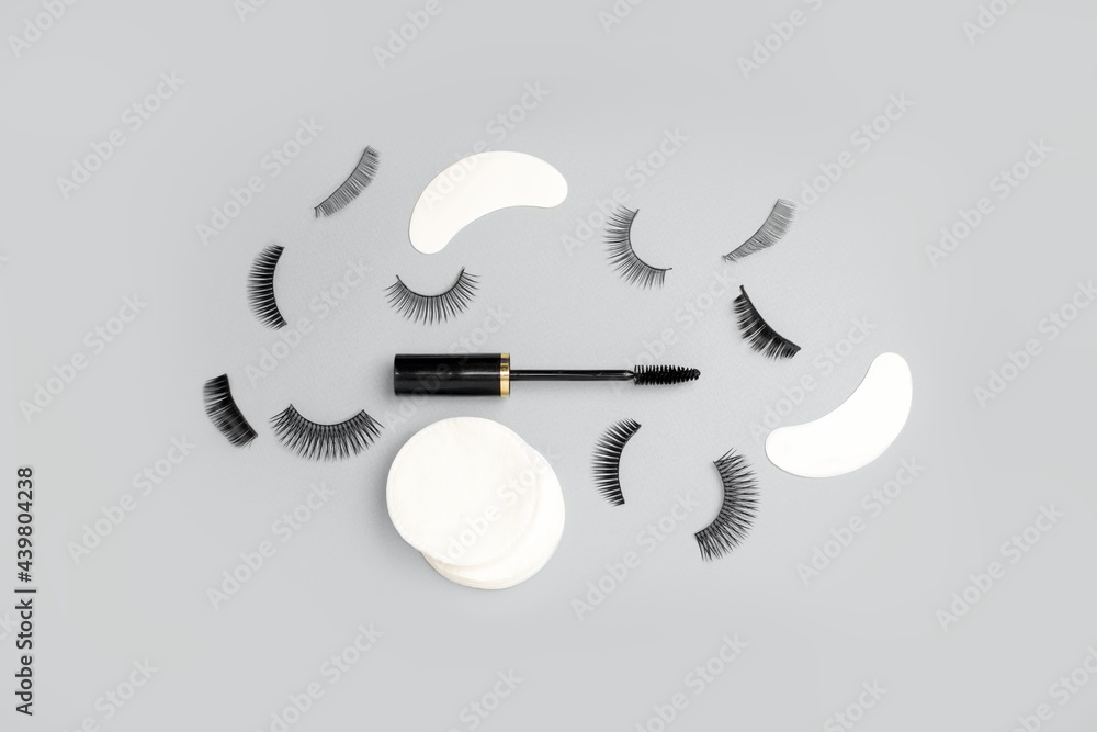 Wall mural Set for eye lash extension on trendy gray background. Fake eyelashes, mascara brush, cotton pads. Beauty concept, makeup cosmetics. Place for text and design. Banner, flyer