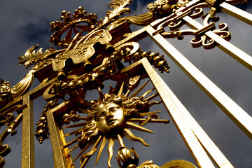Slow travel Paris - new light on familiar sights: Golden sun symbol on the gate to a palace