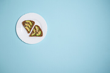 top view of healthy vegetarian sandwich with avocado and seed on blue background