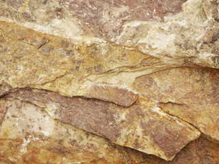 The texture of the red-colored stone is shot close-up. Background with stone texture. Stone layers, cracks in the stone. Yellow-red stone.