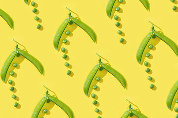 Ripe pod of green pea with small round peas on yellow background. Creative pattern.