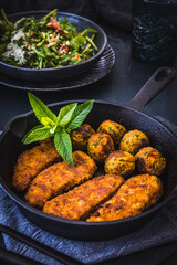 Vegetarian nuggets and vegan balls in an iron pan on dark background, healthy food, vertical