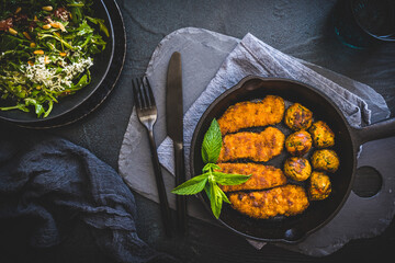 Vegetarian nuggets and vegan balls in an iron pan on dark background, healthy food, top view